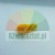 Kleines gelbes Kunststoffteil in Keilform mit oberem Clip auf einfarbigem Hintergrund.