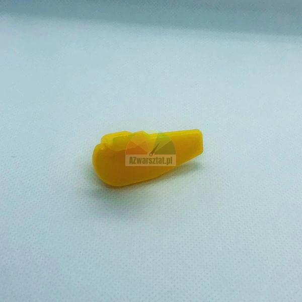 Kleines gelbes Kunststoffteil in Keilform mit oberem Clip auf einfarbigem Hintergrund.