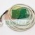 Grüne Leiterplatte PCB mit angelötetem weißem Kabel und Stecker auf weißem Hintergrund.