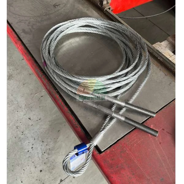 Aufgerolltes Stahlseil mit Gewindeenden und einer Schlaufe auf einer Metallwerkbank.