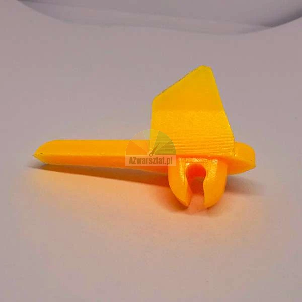 Gelbe Kunststoffkomponente mit einer Finne und einer kleinen Klemme, wahrscheinlich ein 3D-Druckteil.