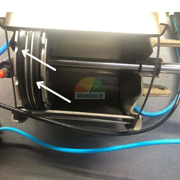 Innenansicht eines pneumatischen Mechanismus mit durch weiße Pfeile gekennzeichneten Kolbendichtungen.