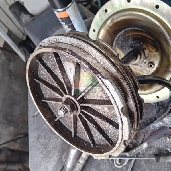 Metallisches mechanisches Bauteil, eine gerippte Riemenscheibe oder Bremstrommel auf einer zentralen Schraube in einer Werkstatt.